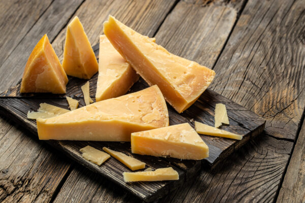 Parmesan cheese on a wooden board, Hard cheese on a dark background. top view